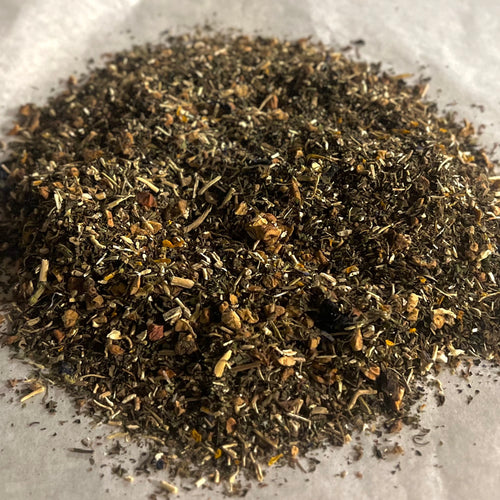 Close-up of loose Mood LIFT wellness tea blend with adaptogenic herbs and natural ingredients on a white surface.