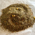 Close-up of loose Rooibos Carrot Cupcake tea blend with cinnamon, candied pieces, and warm spices on white surface