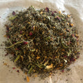 Close-up of Radiant | Her herbal tea blend with mixed dried leaves, flower petals, and nourishing herbal ingredients on parchment paper