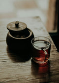 Tea pot and glass of tea on a wooden surface
